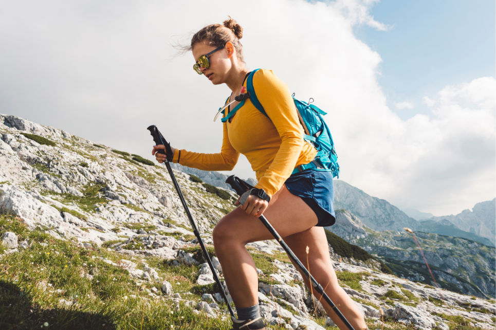Woman hiking on a mountain trail with trekking poles and a backpack
