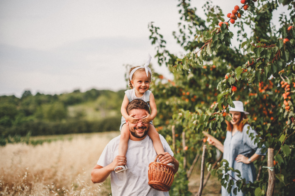 Child sitting on an adult’s shoulders during a family walk outdoors