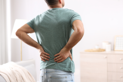 Man holding his lower back while standing indoors