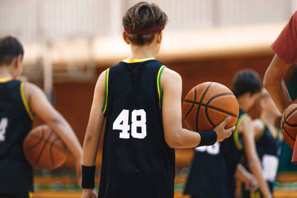 Young basketball players holding basketballs during indoor training
